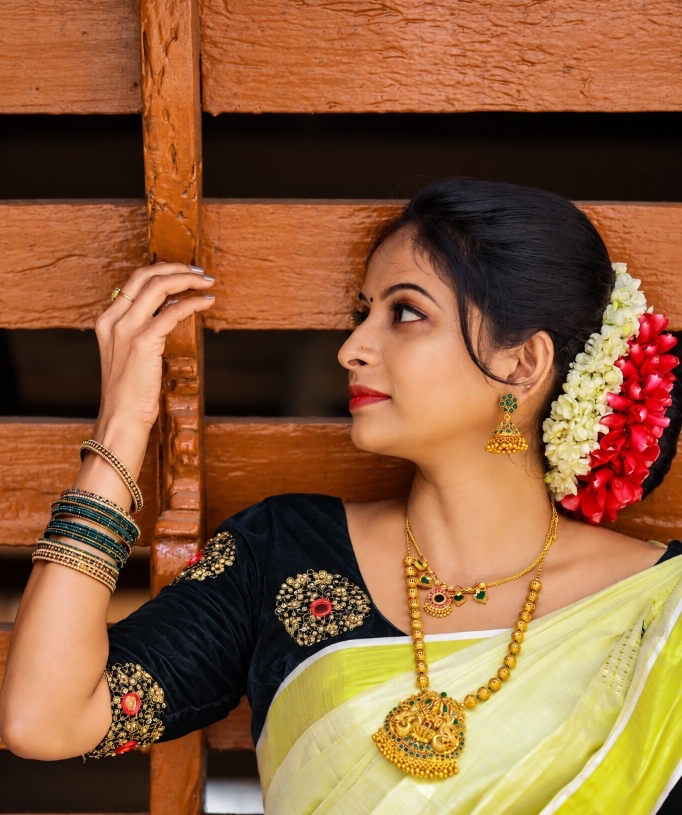 Traditional Kerala bridal beauty styling with jasmine floral hair adornment, temple jewelry, and Kasavu saree